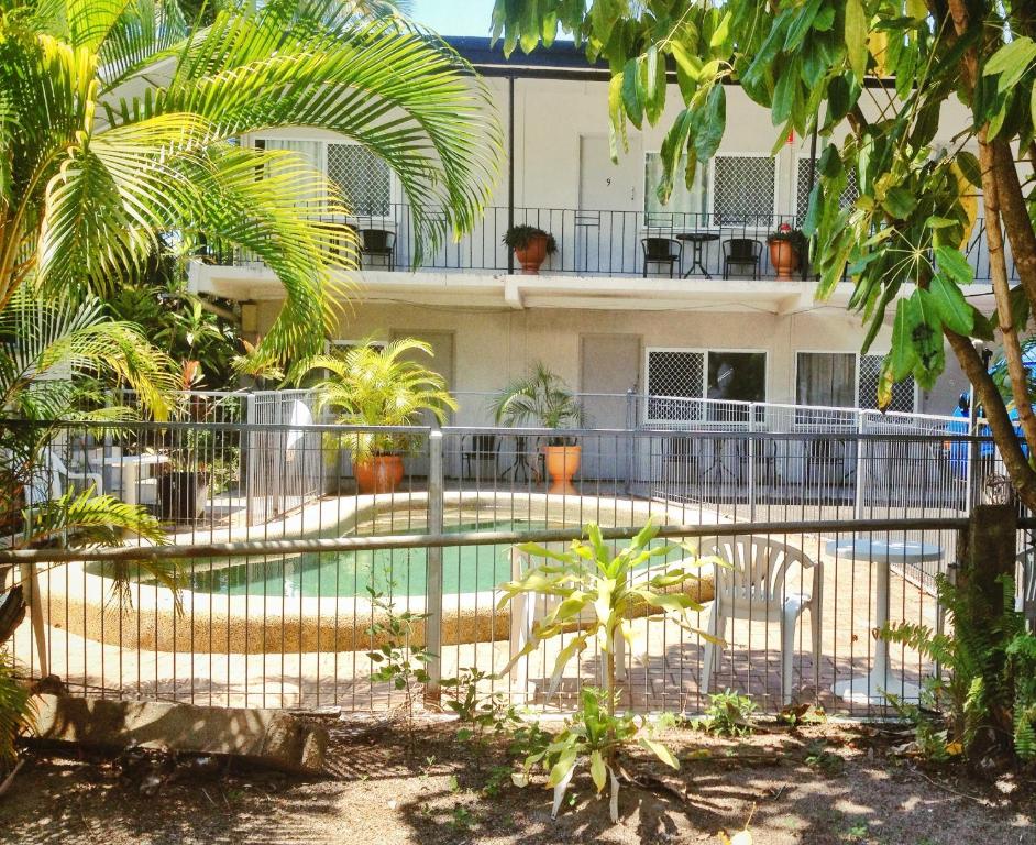 a swimming pool in front of a building with trees at Cairns City Motel in Cairns