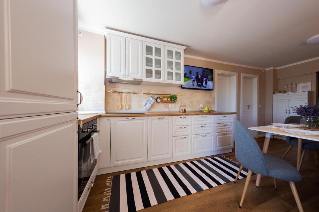 a kitchen with white cabinets and a table and a blue chair at Apartament ALBA CAROLINA in Alba Iulia