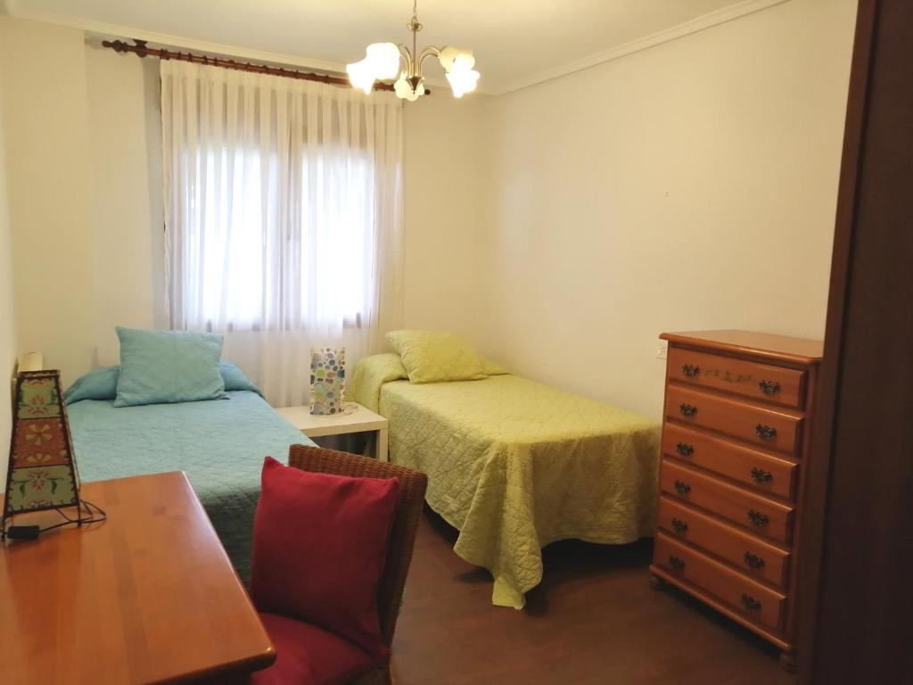 a bedroom with two beds and a table and a dresser at APARTAMENTO RIO AGÜERA EN GURIEZO, next to Castro Urdiales y Bilbao in Adino
