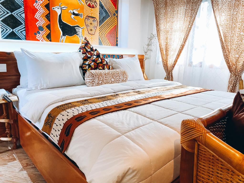 um quarto com uma cama grande com lençóis brancos e almofadas em Ike's Cultural Village em Kumasi