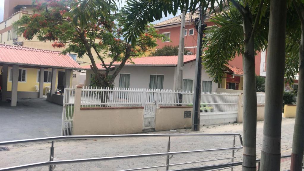 a building with a white fence and some buildings at Residencial Cecilia Cruz in Bombinhas