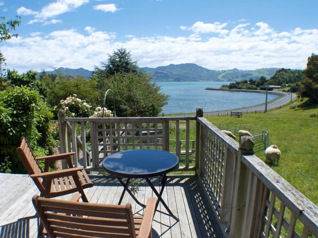 eine Terrasse mit 2 Stühlen, einem Tisch und einem Hund in der Unterkunft Roselle Farm Cottage in Portobello