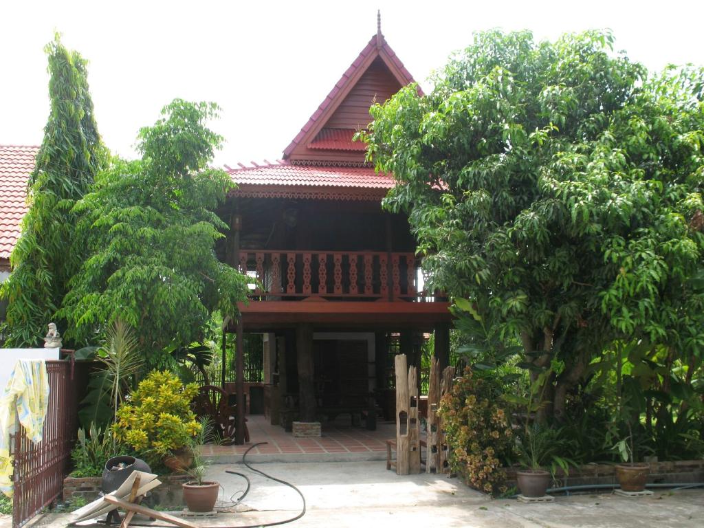a house with trees in front of it at Teak house Chiang Mai in Chiang Mai