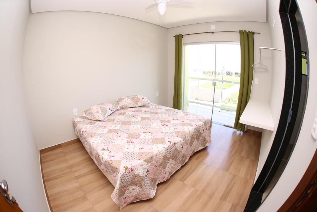 um quarto com uma cama e uma grande janela em Pousada Pérola Mineira em Piumhi