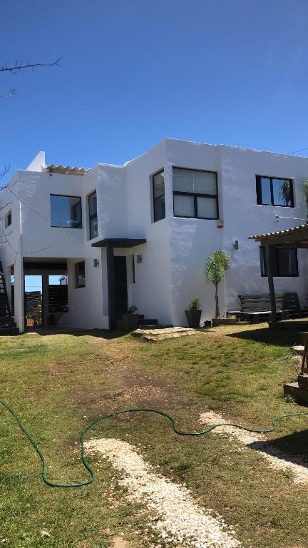 uma casa branca com uma mangueira verde no quintal em Estrella de Mar em La Paloma
