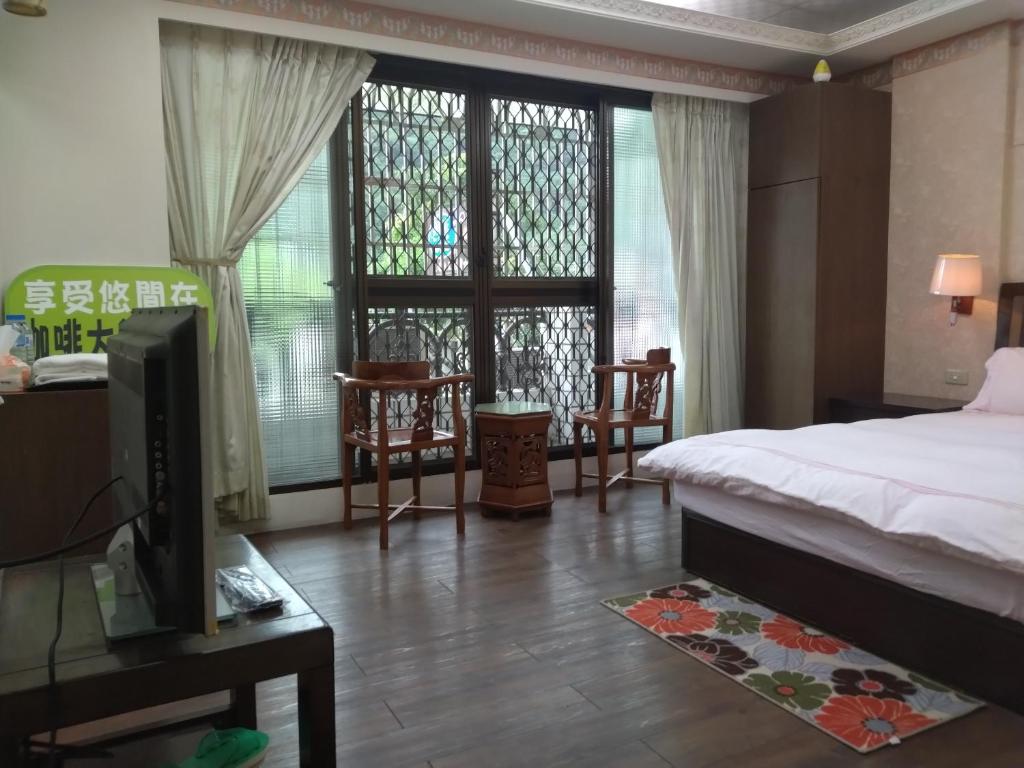 a bedroom with a bed and a tv and a window at Coffee Street Homestay in Gukeng