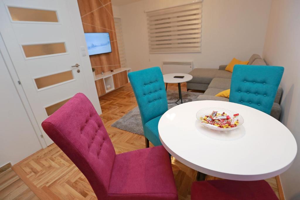 a room with a table and chairs with a bowl of candy at Apartman Una in Pale