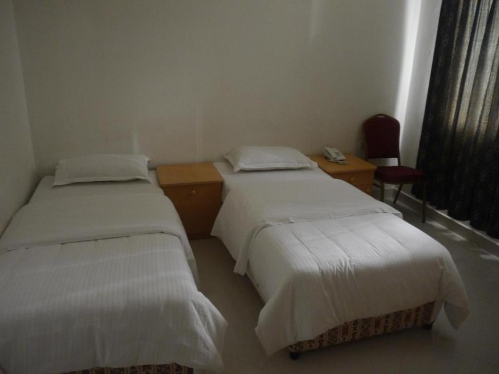 a room with two beds and a desk and a chair at Plaza Hotel in Muscat