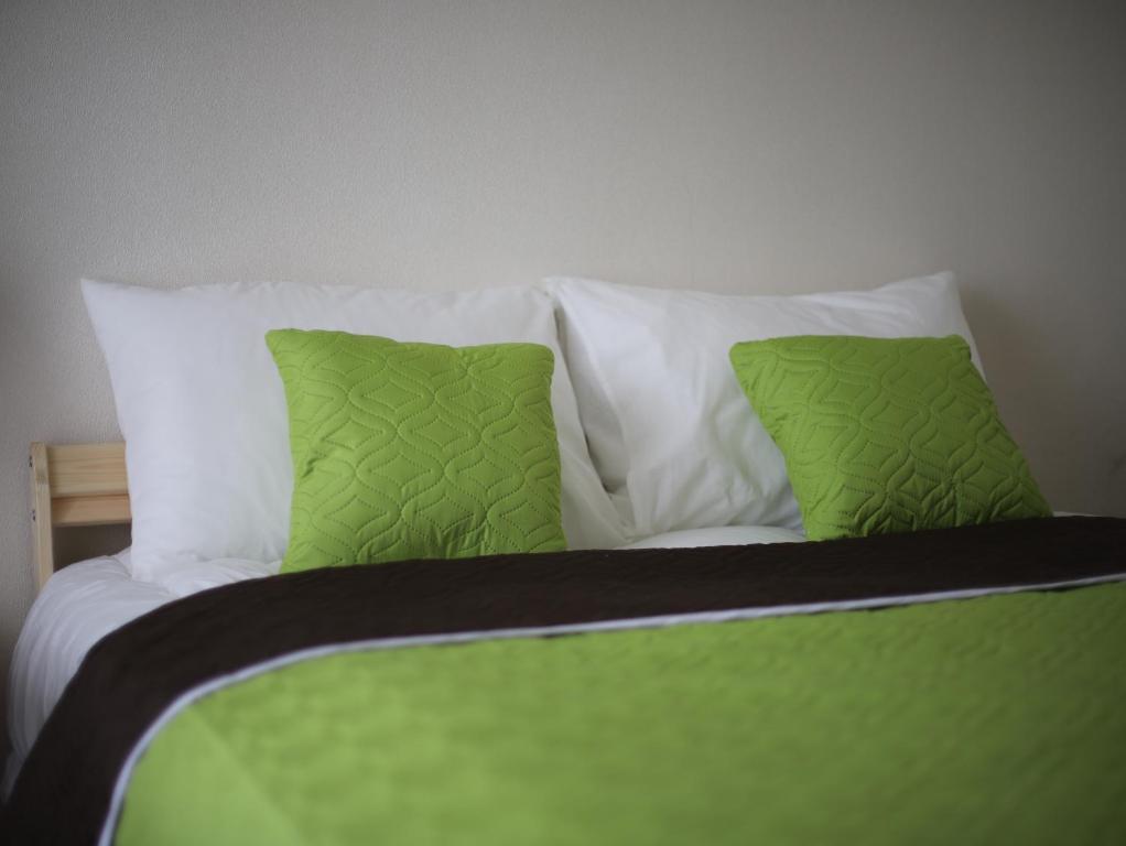 a green and white bed with two green pillows at Ural Apartment in Chelyabinsk