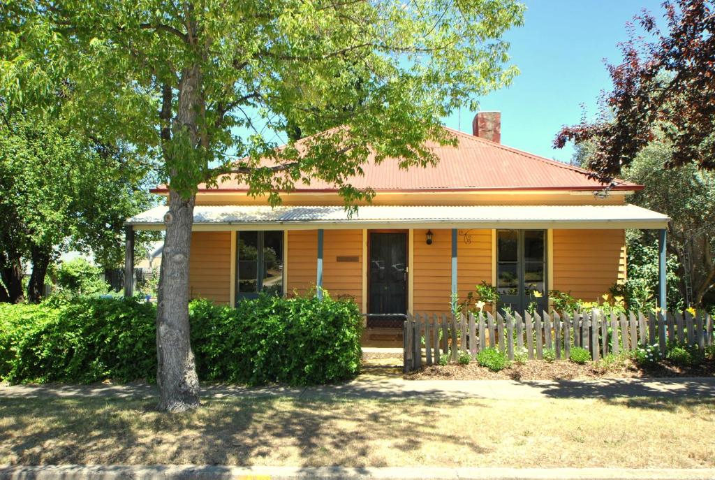 a yellow house with a tree in front of it at Cooma Cottage in Cooma