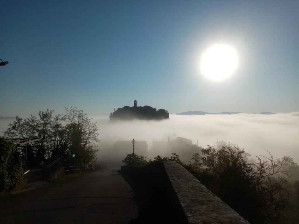 uma vista de uma estrada nebulosa com o sol ao fundo em La Sorpresa Di Civita em Bagnoregio