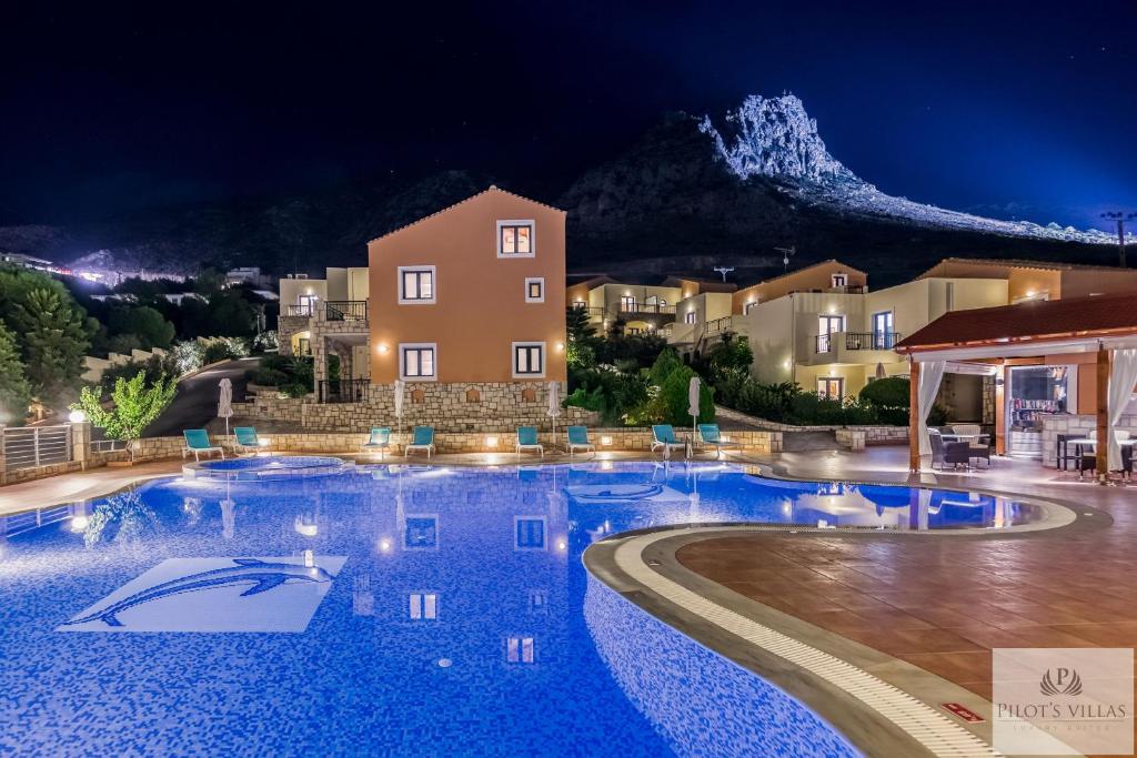 a swimming pool at night with a mountain in the background at Pilot's Villas Luxury Suites in Hersonissos