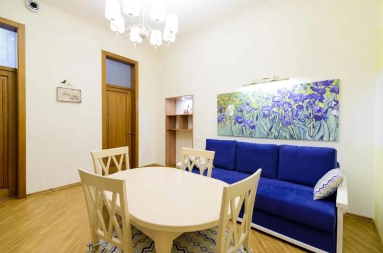 een woonkamer met een blauwe bank en een tafel bij Сучасні Апартаменти на Площі Ринок з балконом in Lviv