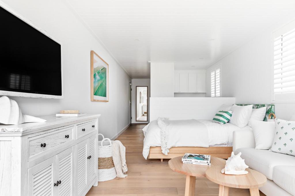 a white living room with a couch and a tv at The Bungalows at Bondi in Sydney