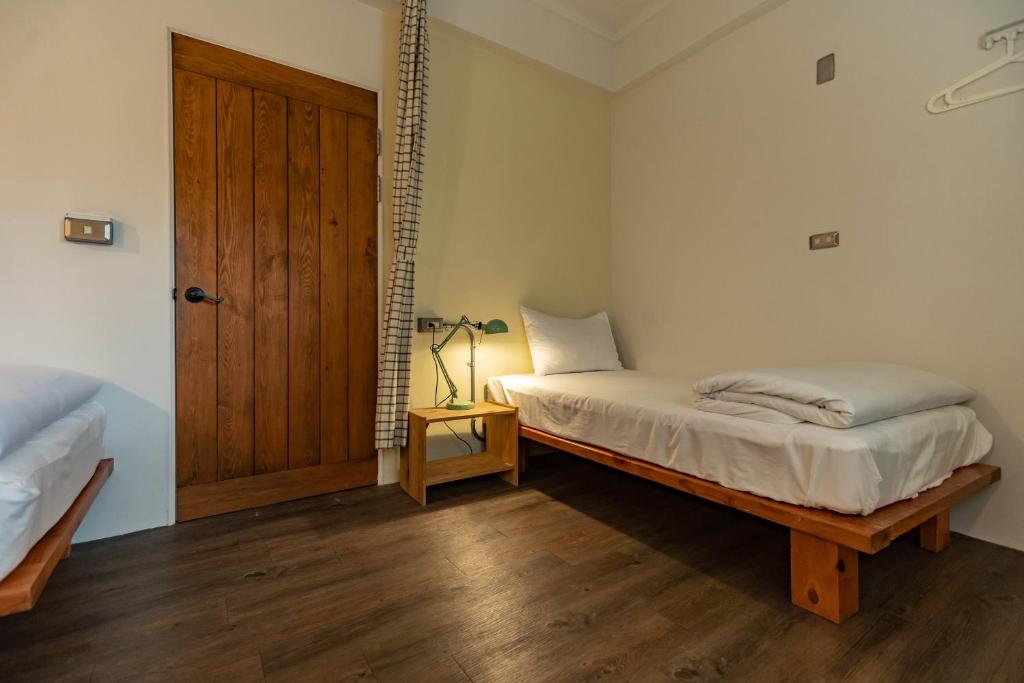 a bedroom with a bed and a wooden door at Cozy House Hostel in Hualien City