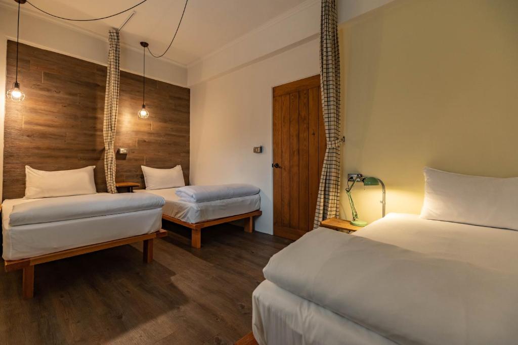a hotel room with two beds and a table at Cozy House Hostel in Hualien City