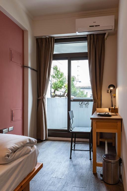 a bedroom with a bed and a desk and a window at Cozy House Hostel in Hualien City