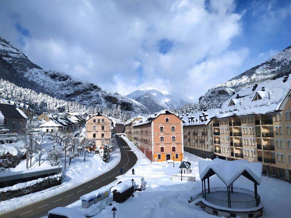 een stad bedekt met sneeuw met bergen op de achtergrond bij Apartamento de montaña "Nueva Canfranc" in Canfranc-Estación