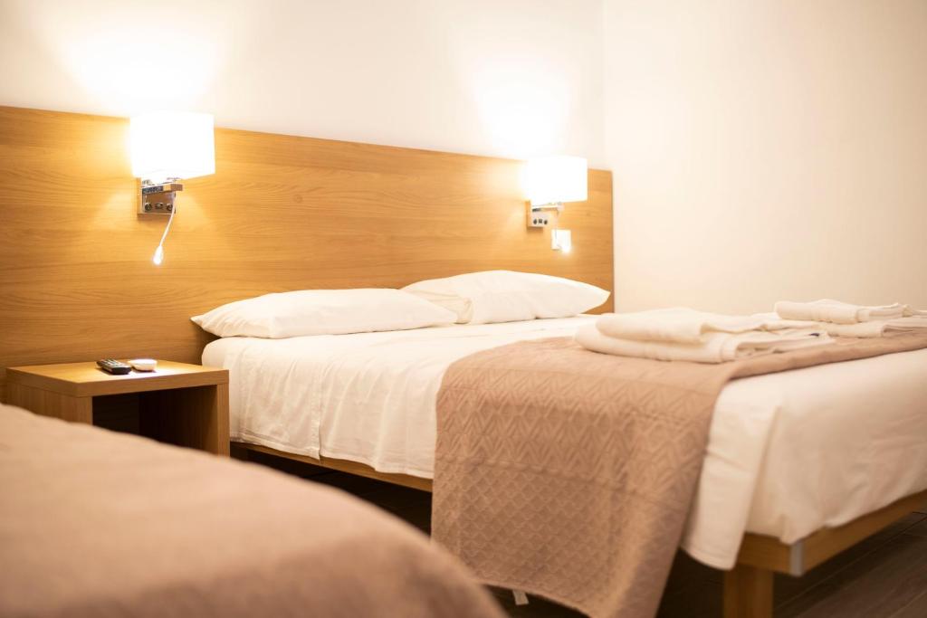 ein Hotelzimmer mit 2 Betten mit weißer Bettwäsche in der Unterkunft Musa B&B in Taranto