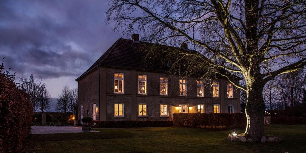 una casa grande con sus luces encendidas por la noche en Lindegaarden Kollund, en Kruså