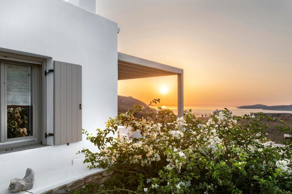 un coucher de soleil à travers une fenêtre d'une maison dans l'établissement White Tinos Luxury Suites, à Stení