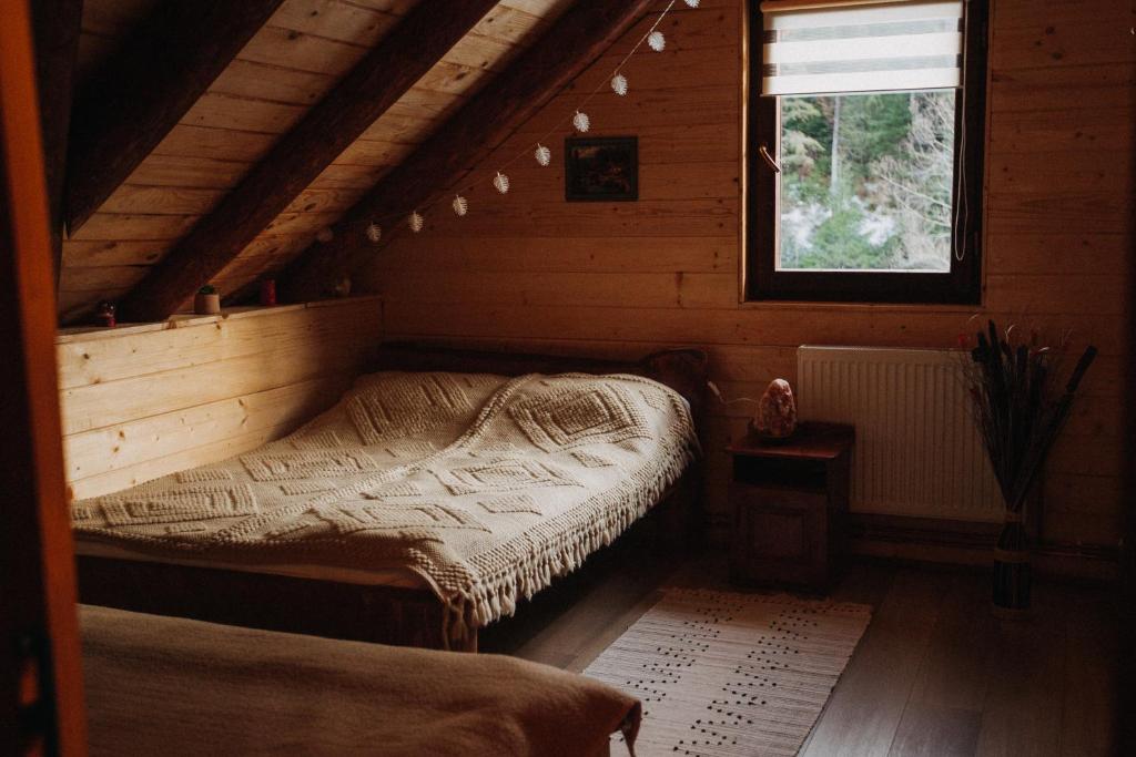 a bedroom with a bed in a wooden cabin at Csángó Panoráma in Valea Rece