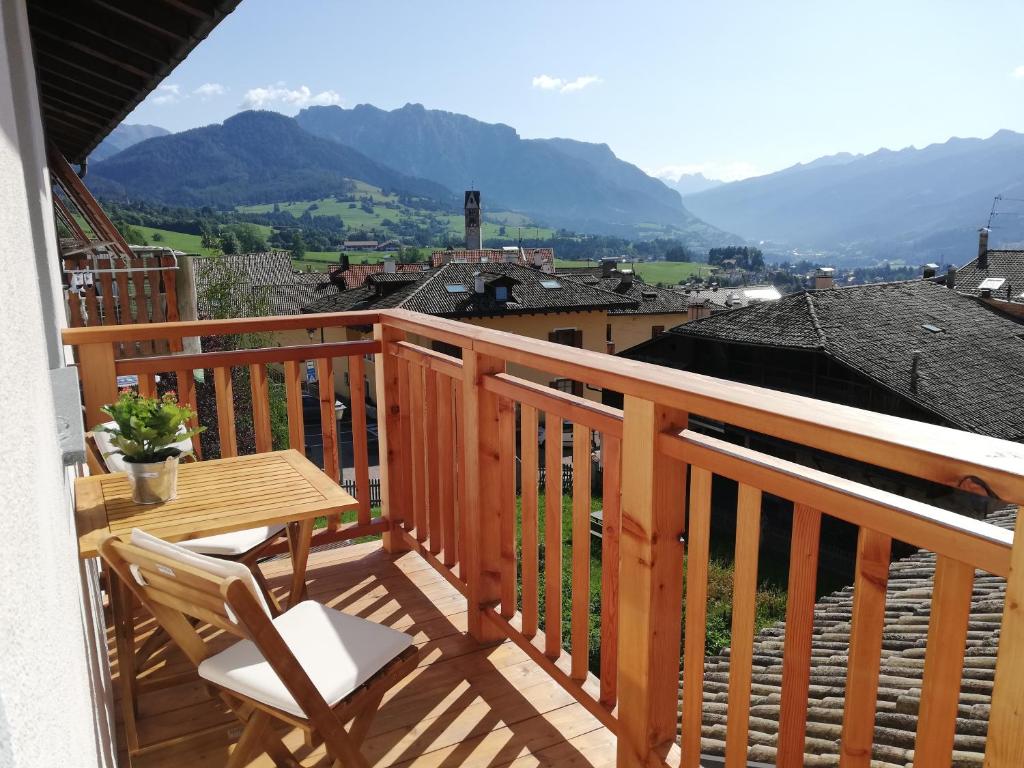 a wooden balcony with a table and chairs and mountains at Casa Lassù in Carano