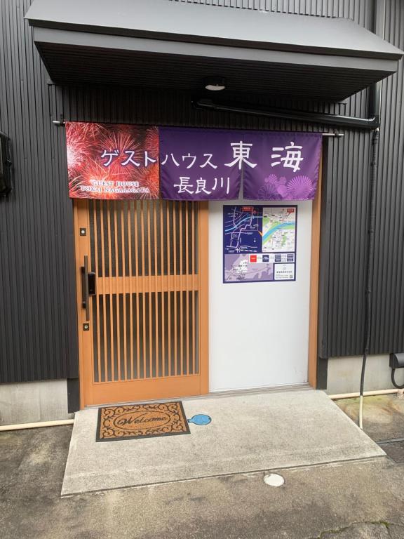 eine Tür zu einem Gebäude mit einem Schild darauf in der Unterkunft ゲストハウス・東海　長良川 in Gifu
