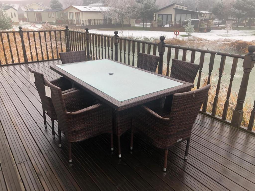una mesa de madera y sillas en una terraza con nieve en Waterside Retreat en Tydd Saint Giles