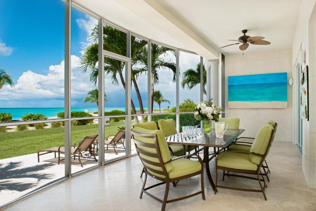 a dining room with a table and chairs and the ocean at The Venetian on Grace Bay in Grace Bay