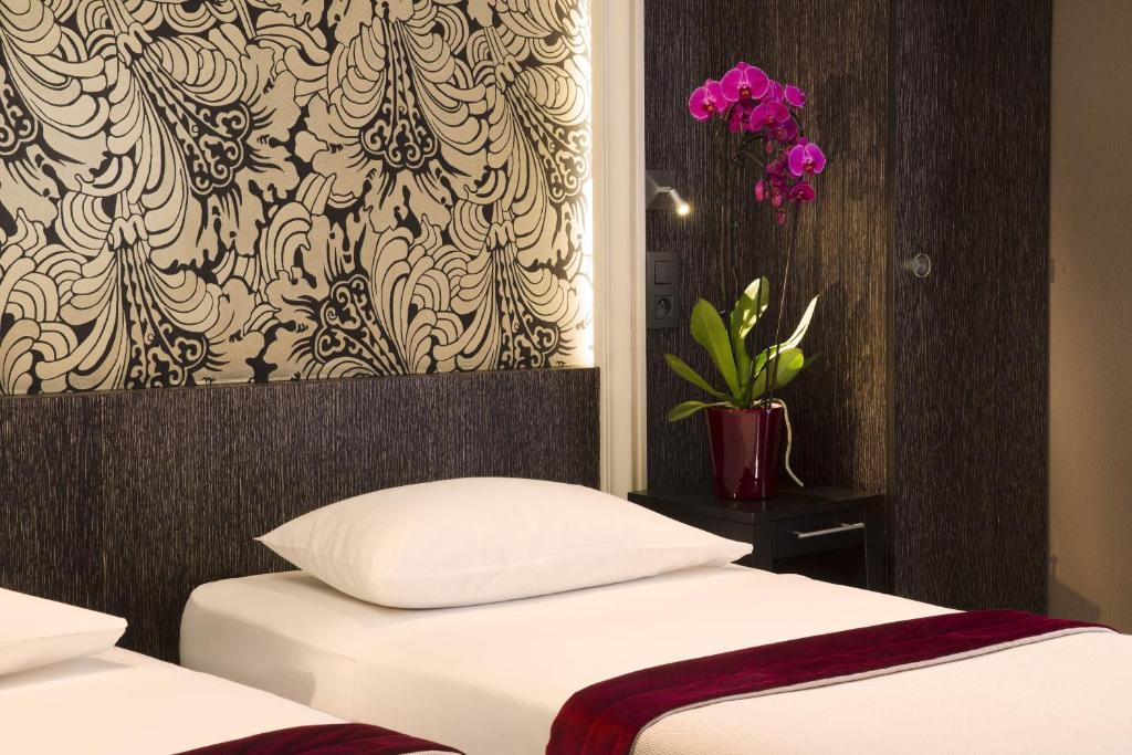 1 Schlafzimmer mit 2 Betten und einer Vase mit lila Blumen in der Unterkunft Central Hotel Paris in Paris