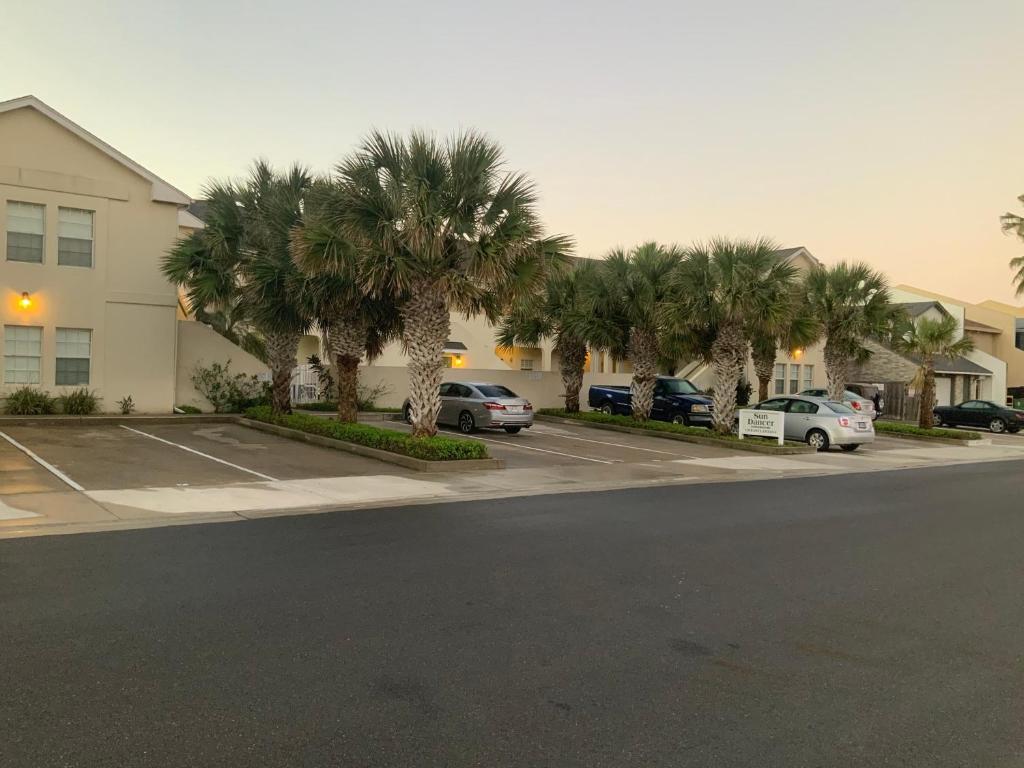 ein Parkplatz mit Palmen vor einem Gebäude in der Unterkunft Sun Dancer #11 in South Padre Island