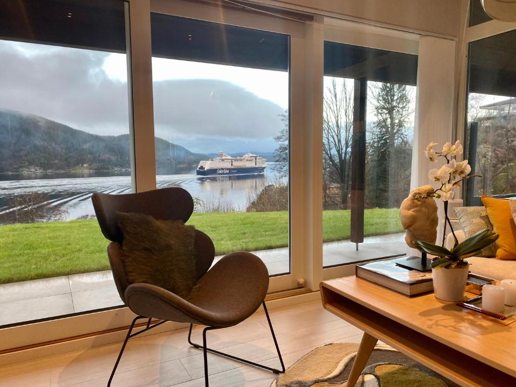 ein Wohnzimmer mit einem Tisch, einem Stuhl und einem großen Fenster in der Unterkunft Funky cabin with a panoramic view of the Oslofjord in Nordre Frogn
