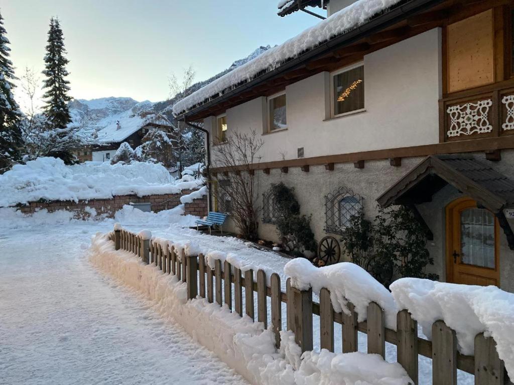 una casa cubierta de nieve junto a una valla en Appartamento Neif de Sellaronda, en Campitello di Fassa