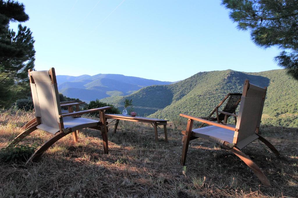 Gites-Terroirs-Occitanie في Felluns: كرسيان يجلسون على تلة مع جبال في الخلفية