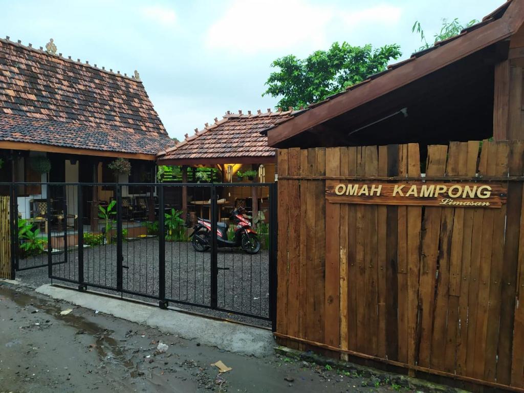 a wooden fence with a gate with a motorcycle behind it at Omah Kampong in Yogyakarta