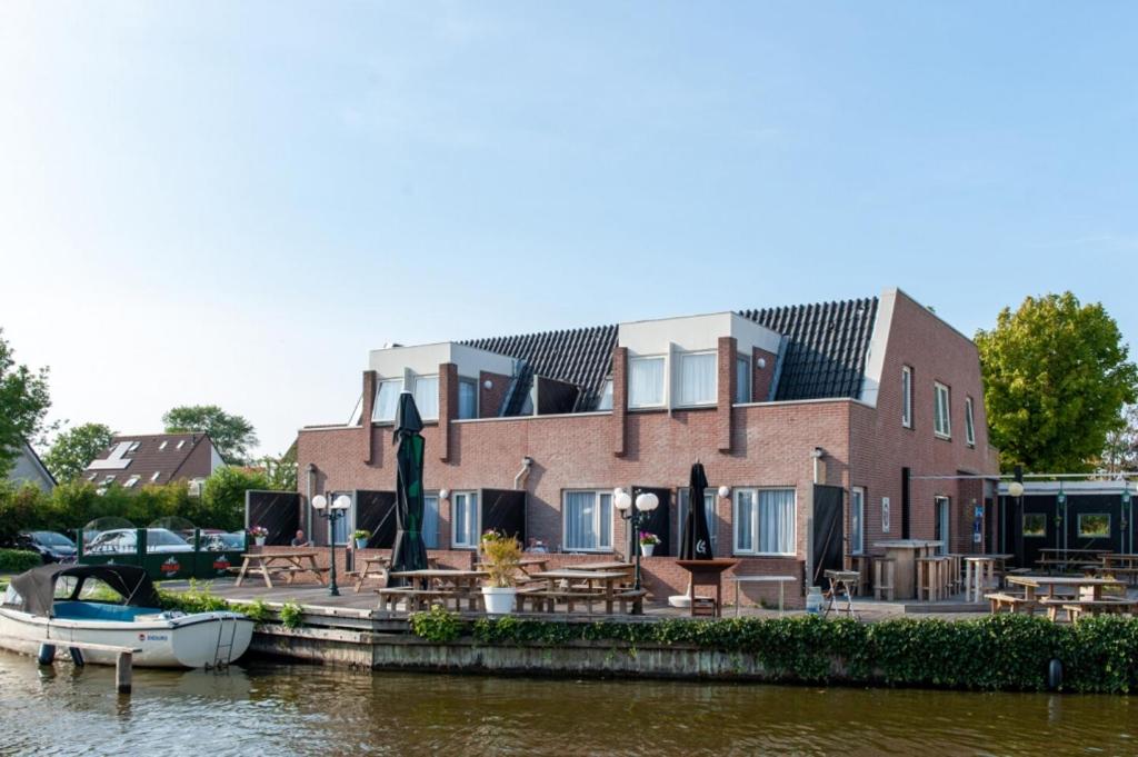 una casa en el agua con mesas y un barco en De Watersport Heeg en Heeg