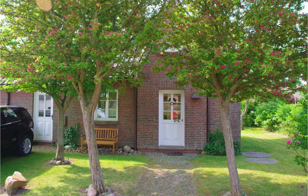 uma casa de tijolos vermelhos com duas árvores em frente em Lovely Home In Dithmarschen With Kitchen 