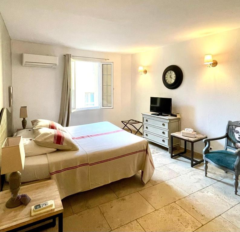 a bedroom with a bed and a tv and a chair at Un Coin De Luberon in L'Isle-sur-la-Sorgue