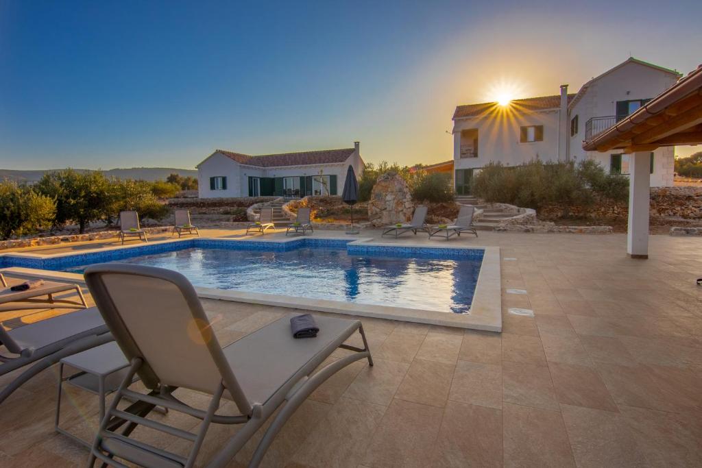 a swimming pool with chairs and a house at Villa Luisa Pucisca - 2 Häuser, 6 Schlafzimmer Insel Brac - Pool, Grill, Kamin, Tischtennis, Boccia in Pučišća