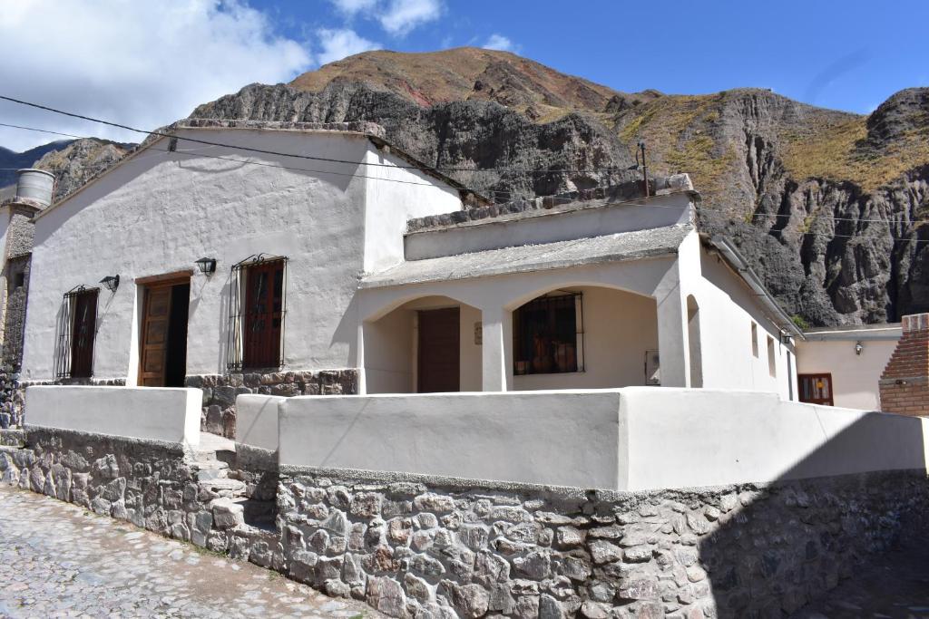 a white house with a stone wall in front of a mountain at El Caucillar in Iruya