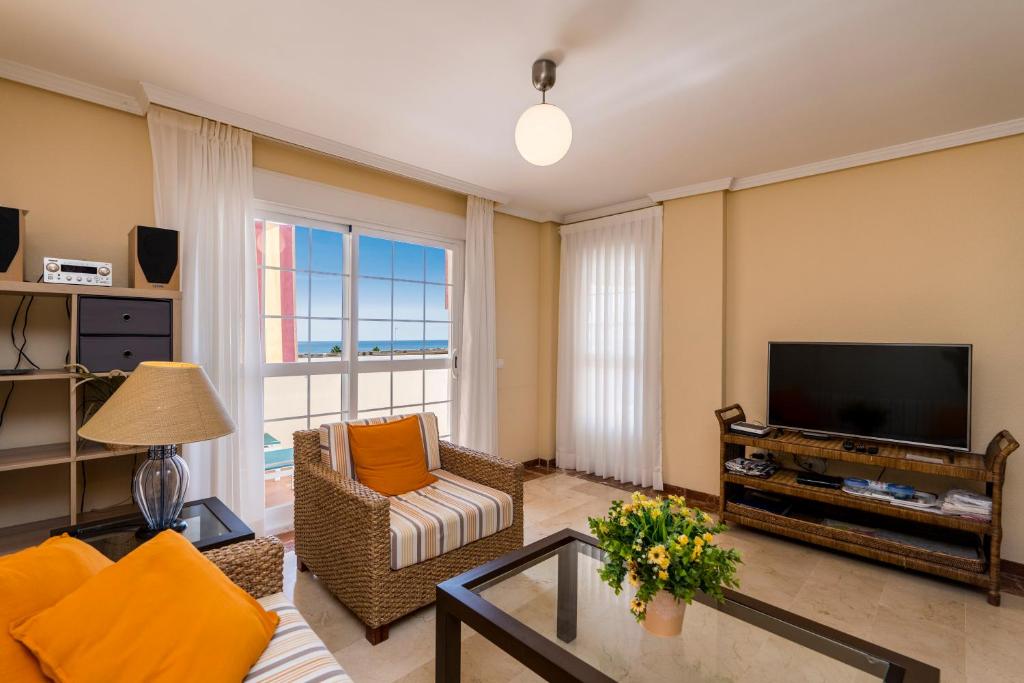 een woonkamer met een televisie, een bank en een tafel bij Apartamento Torreón del Mar 100m de la playa garage in Benalmádena