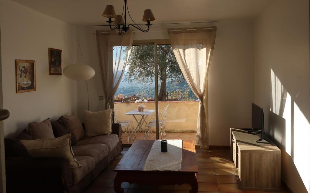 un salon avec un canapé, une table et une fenêtre dans l'établissement Appartement spacieux et chaleureux à Grasse, à Grasse