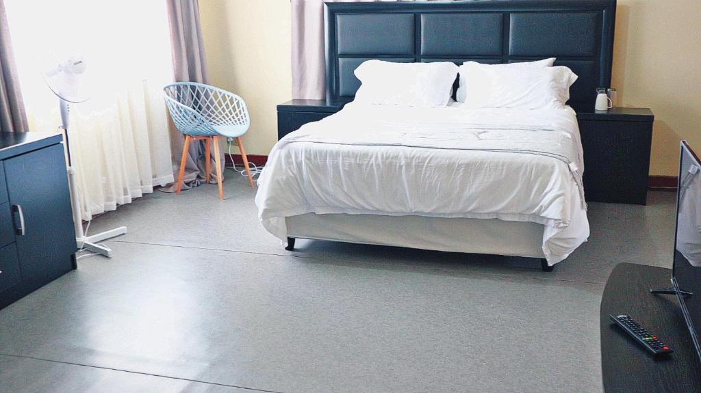 a bedroom with a large bed and a blue chair at Langton Guesthouse in Durban