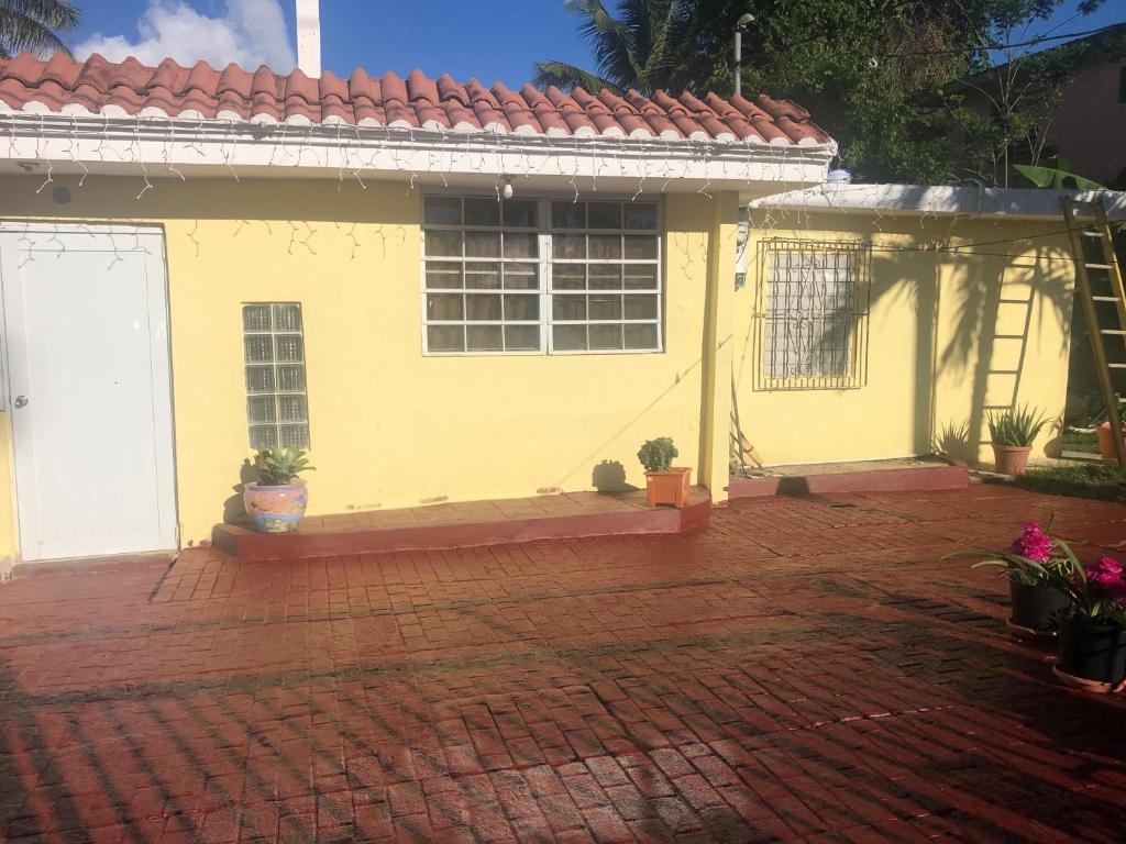 Casa amarilla con techo rojo y entrada de ladrillo en Gavidias Guest House, en San Lorenzo