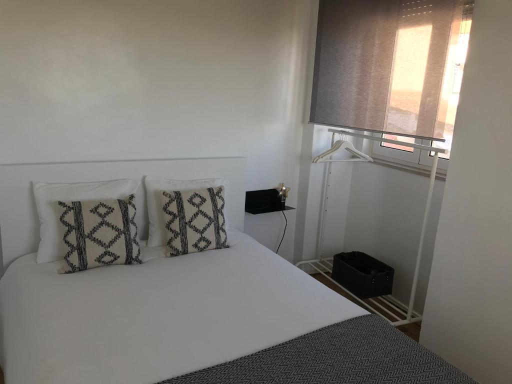 ein Schlafzimmer mit einem weißen Bett mit Kissen und einem Fenster in der Unterkunft Silvirhouse in Peniche