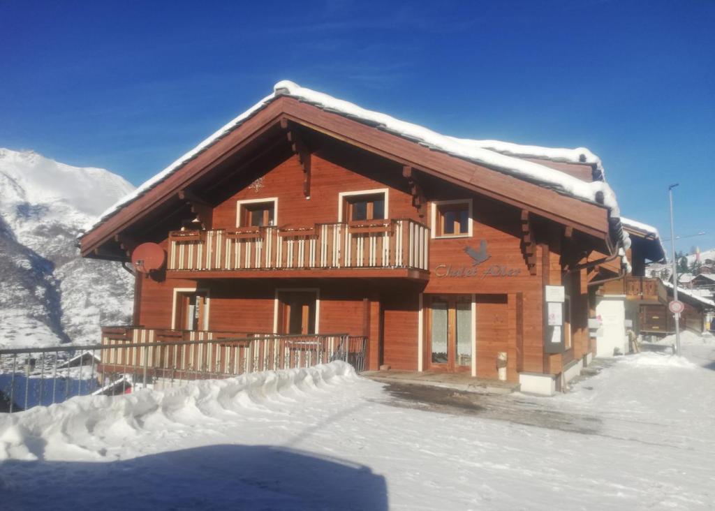 una cabaña de madera con nieve en la parte delantera en Chalet Adler, en Grächen