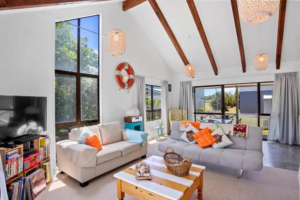 a living room with two couches and a table at Coastal Charm - Waihi Beach Holiday Home in Waihi Beach