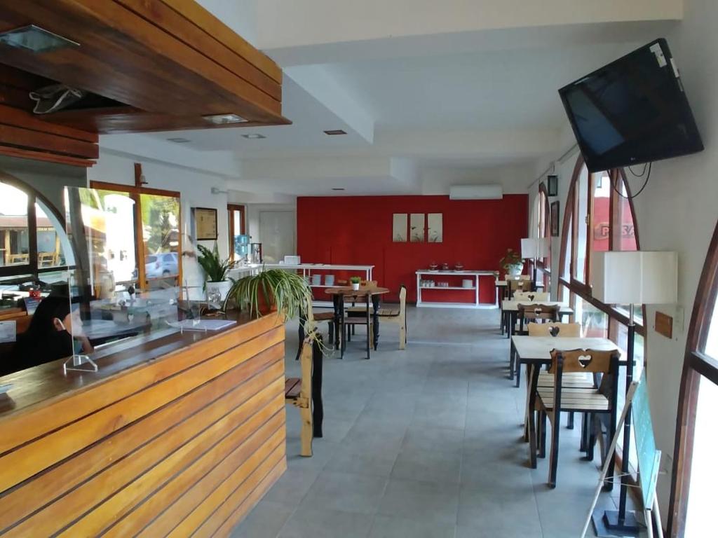 un restaurante con mesas y sillas y TV de pantalla plana en Posada Mia Nonna en Villa General Belgrano