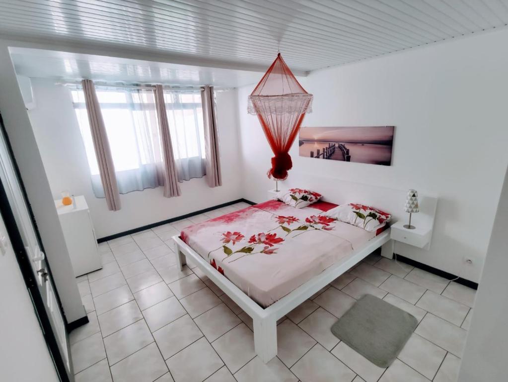 um quarto branco com uma cama com flores em Dany Lodge - Spacieux T2 à 5 minutes de la plage en voiture em Rivière-Pilote
